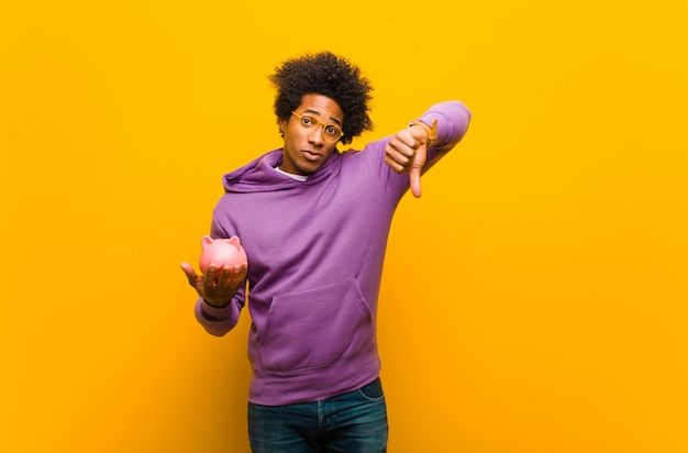 Young african american man with a piggy bank