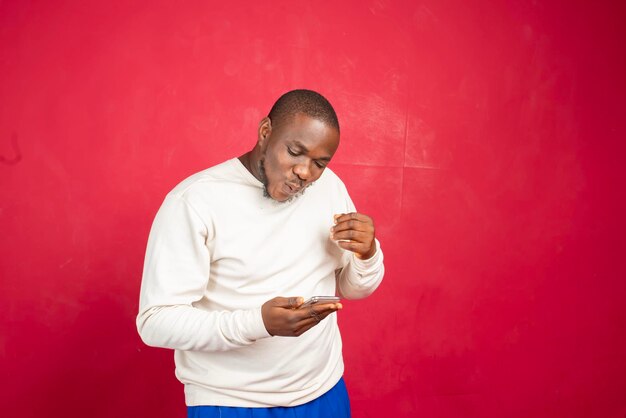 Young african american man with surprised facial expression hold smartphone