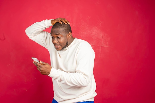 Photo young african american man with surprised facial expression hold smartphone