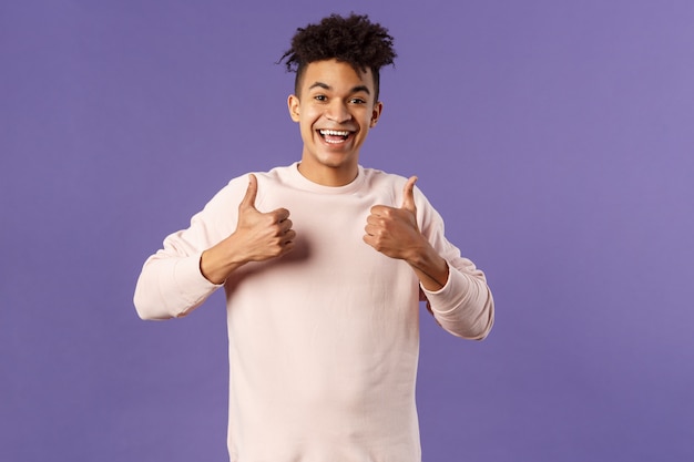 Young African American man in yellow shirt showing gesture.