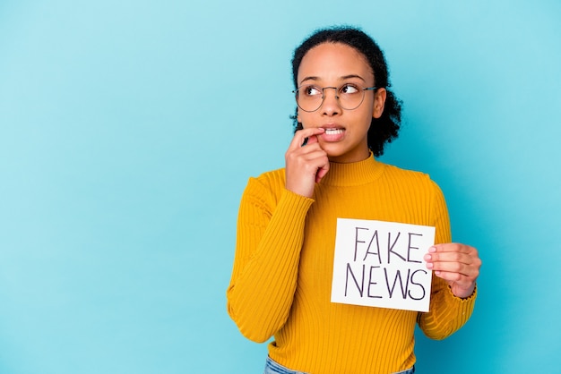 Young african american mixed race woman holding a fake news concept relaxed thinking about something looking at a copy space.