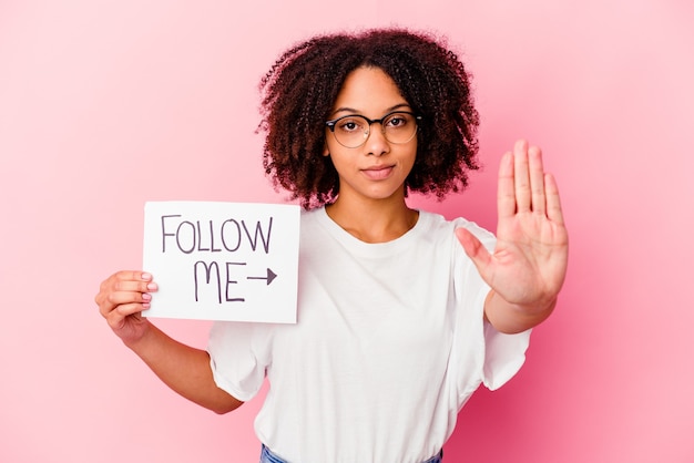 Young african american mixed race woman holding a follow me concept standing with outstretched hand showing stop sign, preventing you.