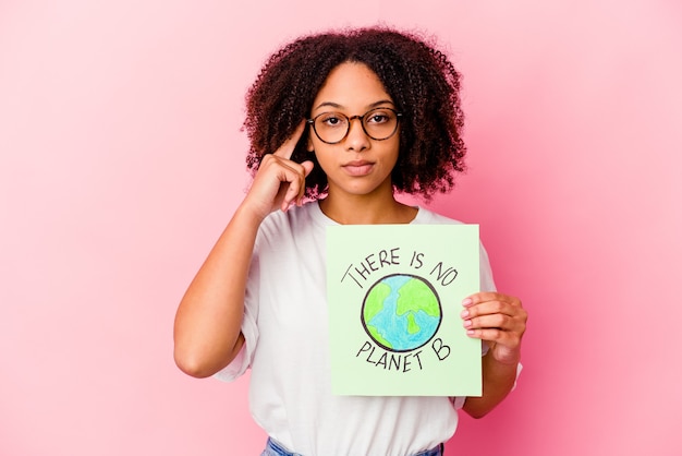 Young african american mixed race woman holding a world protection concept cardboard pointing temple with finger, thinking, focused on a task.