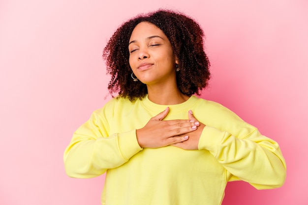 Young african american mixed race woman isolated has friendly expression, pressing palm to chest. Love concept.