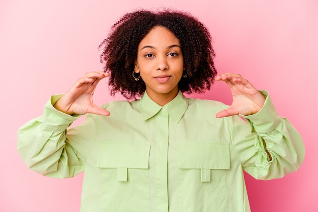 Young african american mixed race woman isolated holding something with palms, offering to camera.