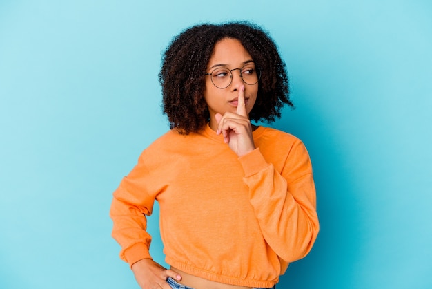 Young african american mixed race woman isolated keeping a secret or asking for silence.