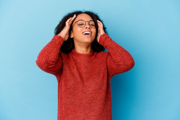 Photo young african american mixed race woman isolated laughs joyfully keeping hands on head. happiness concept.