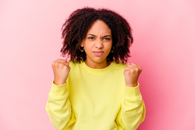 Young african american mixed race woman isolated showing fist, aggressive facial expression.