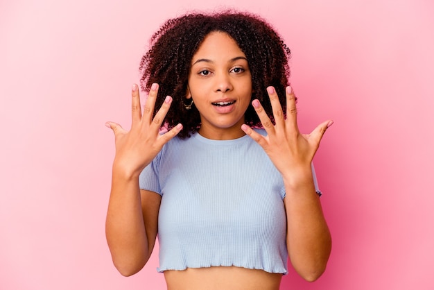 Молодая афро-американская женщина смешанной расы изолирована, показывая номер десять руками.