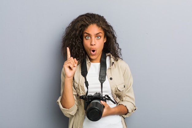 Young african american photographer woman holding a camera having some great idea, concept of creativity.