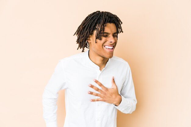 Young african american rasta man laughing keeping hands on heart, concept of happiness.