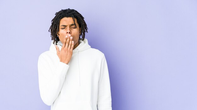 Young african american rasta man yawning showing a tired gesture covering mouth with hand.