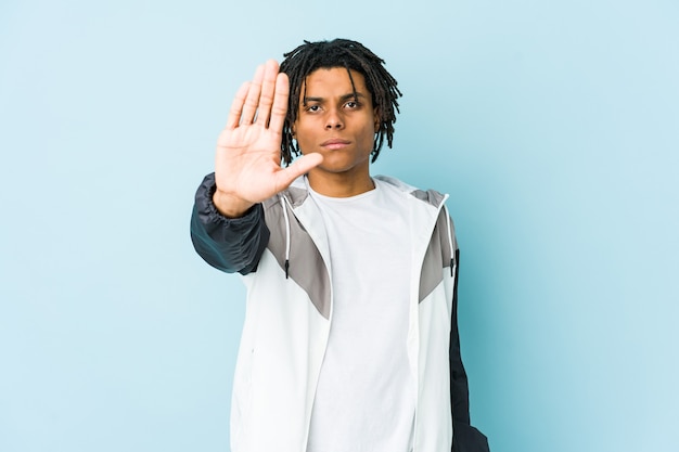 Young african american sport man standing with outstretched hand showing stop sign, preventing you.