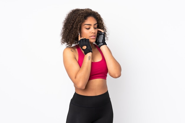 Young African American sport woman on white wall listening music