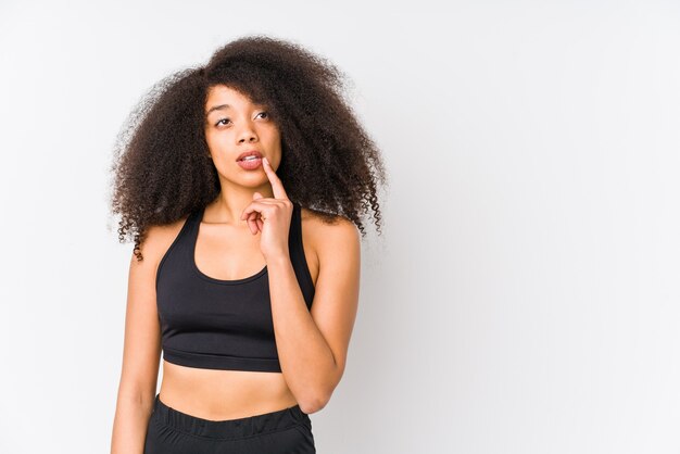 Young african american sporty woman looking sideways with doubtful and skeptical expression.