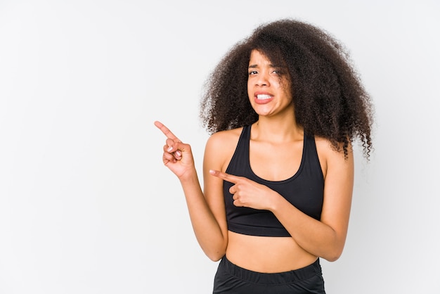 Young african american sporty woman shocked pointing with index fingers to a copy space.