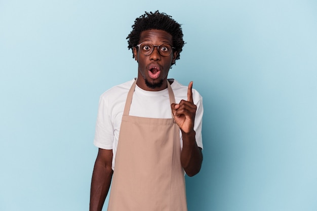 Young african american store clerk isolated on blue background having an idea, inspiration concept.