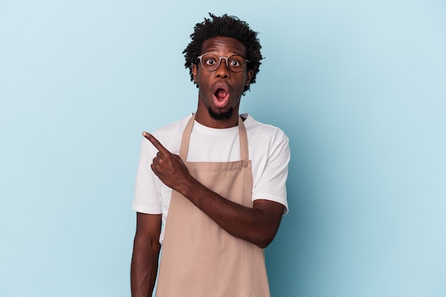 Young african american store clerk isolated on blue background pointing to the side