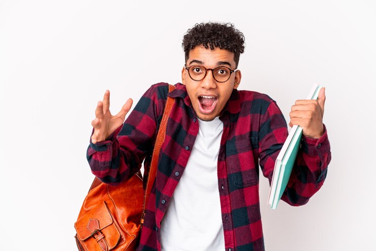 Photo young african american student curly man isolated holding books receiving a pleasant surprise, excited and raising hands.