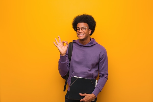 Young african american student man cheerful and confident doing ok gesture