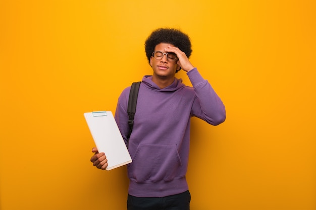 Giovane uomo afroamericano dello studente che giudica una lavagna per appunti preoccupata ed enorme