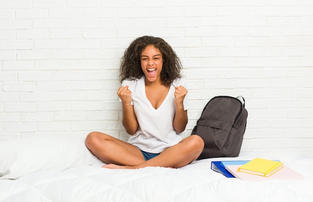 Young african american student woman on the bed cheering carefree and excited. Victory concept.