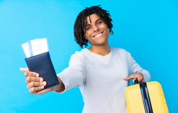 Young African American traveler man holding a suitcase and a passport