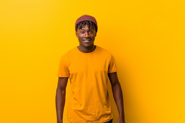 Photo young african american trendy man standing against a yellow  wearing a hat