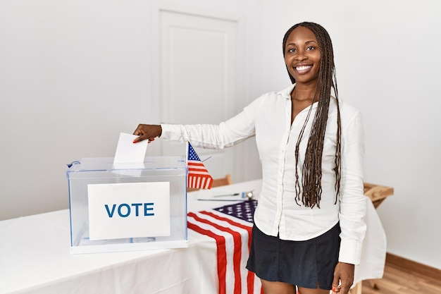 Foto giovane elettore afroamericano che mette il voto nelle urne al collegio elettorale