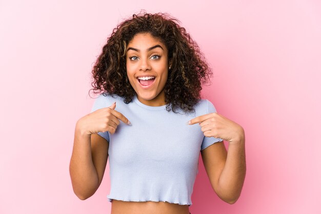 핑크 공간에 대 한 젊은 아프리카 계 미국인 여자는 광범위 하 게 웃 고 손가락으로 가리키는 놀 랐 다.