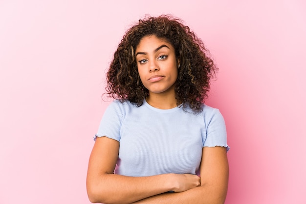 Giovane donna afroamericana contro una parete rosa insoddisfatta dell'espressione sarcastica.