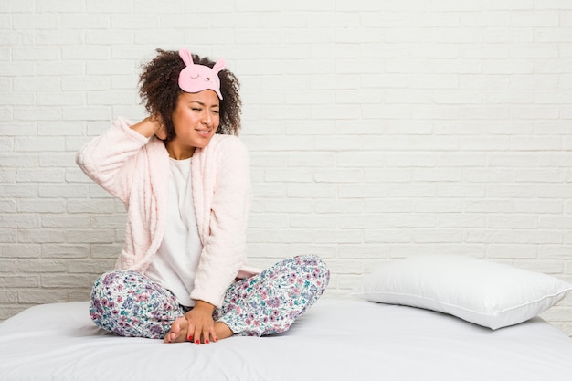 Young african american woman in the bed wearing pijama suffering neck pain due to sedentary lifestyle.