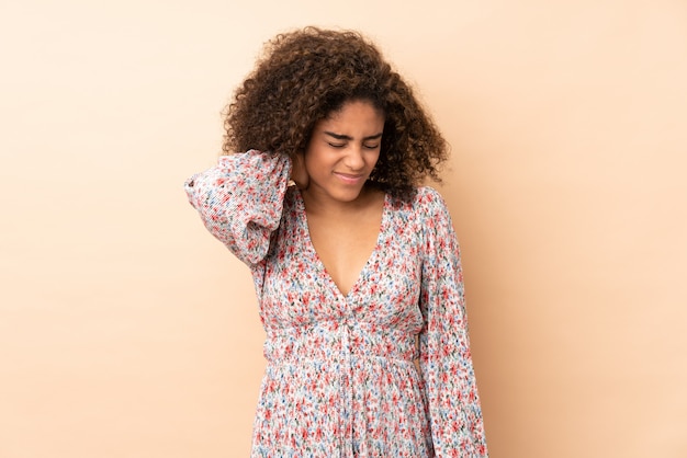 Young African American woman on beige wall with neckache