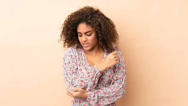 Photo young african american woman on beige wall with pain in elbow