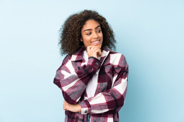 Young African American woman on blue wall looking to the side and smiling