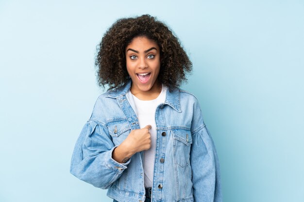 Young African American woman on blue wall with surprise facial expression