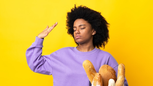 Photo young african american woman buying something bread isolated on yellow background with tired and sick expression