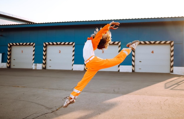 젊은 아프리카계 미국인 여성 댄서가 해가 지는 거리에서 춤을 춘 곱슬머리 스타일리시한 여성