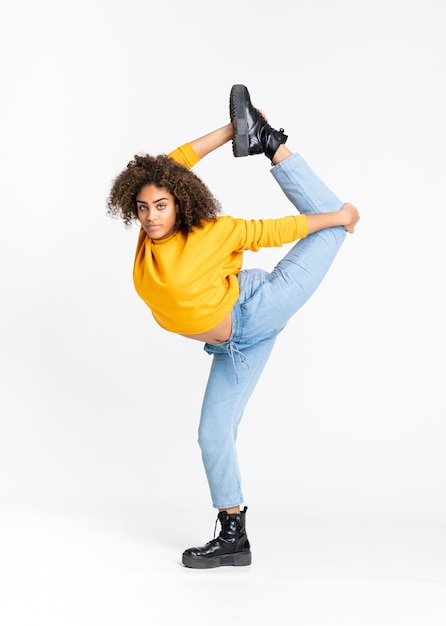 Young African American woman dancing over white wall