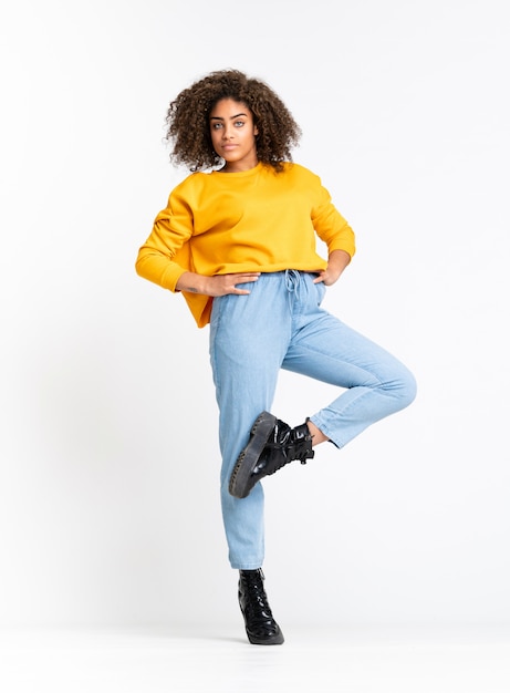 Young African American woman dancing over white wall