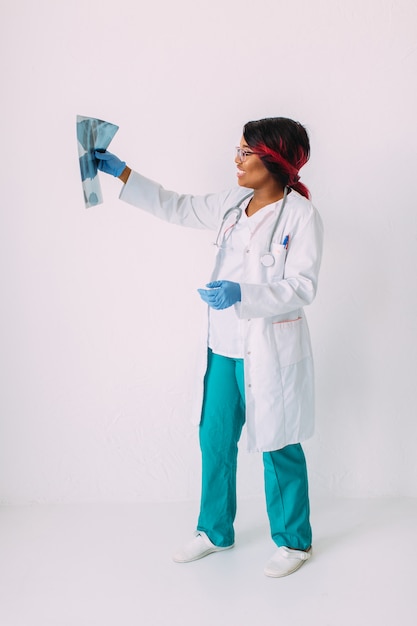 Young African American woman doctor in medical wear looking at x-ray image