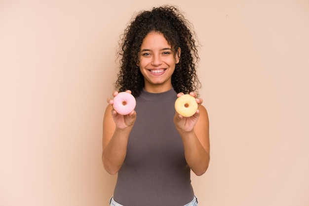 Young african american woman eating doughnut isolated