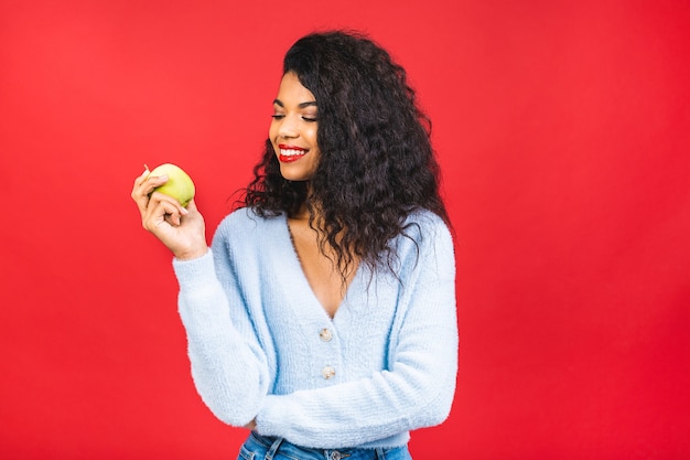 Young african american woman eating green apple