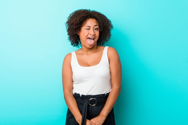 Young african american woman funny and friendly sticking out tongue.