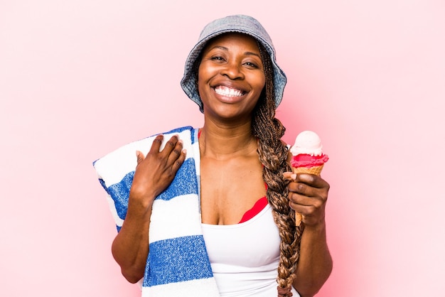 ピンクの背景で隔離のアイスクリームを保持してビーチに行く若いアフリカ系アメリカ人女性