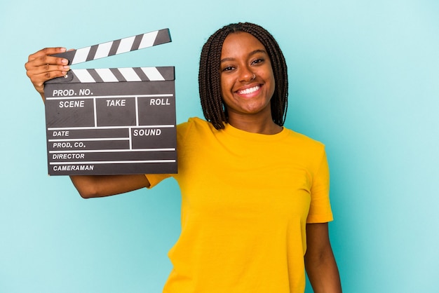 Young african american woman holding a clapperboard isolated on blue background  happy, smiling and cheerful.