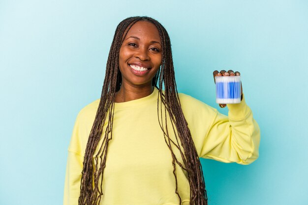 Young african american woman holding cotton bulls isolated on buds background happy, smiling and cheerful.