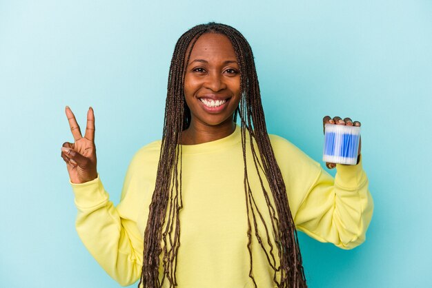 Young african american woman holding cotton bulls isolated on buds background showing number two with fingers.