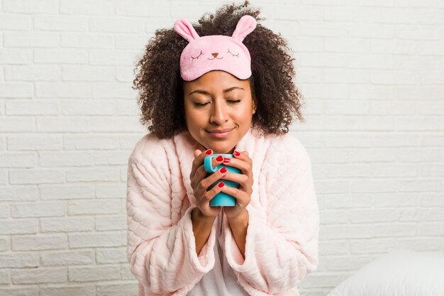 Young african american woman holding a cup on the bed