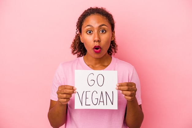 분홍색 배경에 격리된 채식주의자 플래카드를 들고 있는 젊은 아프리카계 미국인 여성